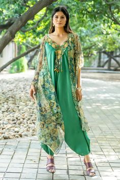 Green jumpsuit with attached charm tassels. Comes with floral pattern cape.
Components: 2
Type Of Work: Floral
Neckline: Jumpsuit: V-neck, Cape: Open
Sleeve Type: Jumpsuit: Sleeveless, Cape: Cape sleeves
Fabric: Net,Raw Silk
Color: Green
Other Details: 
Embroidered jumpsuit neck panel
Occasion: Party - Aza Fashions Green Bohemian V-neck Jumpsuits And Rompers, Bohemian Sleeveless Set For Eid, Festive Floor-length Jumpsuits And Rompers For Summer, Green Tassel Sets For Eid, Green Tassel Set For Eid, Elegant Summer Festive Jumpsuits And Rompers, Cape For Women, Embroidered Jumpsuit, Open Sleeve