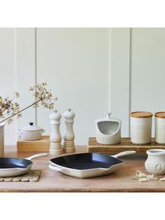 pots and pans are sitting on a table with other kitchen utensils in front of them