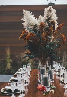 a wooden table topped with lots of glass vases filled with flowers