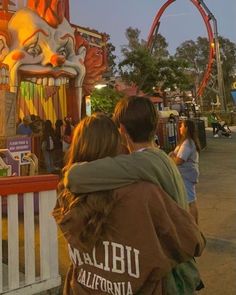 two people standing in front of a carnival ride