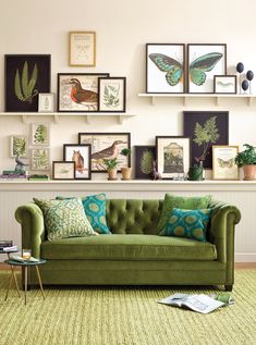 a living room filled with green furniture and pictures on the wall above it's fireplace