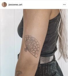 a woman's arm with a fan tattoo on the left side of her arm