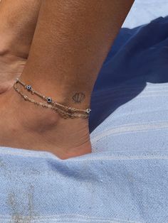 a woman's foot with a tattoo on it and a chain around the ankle