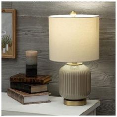 a lamp sitting on top of a table next to a book and a framed picture