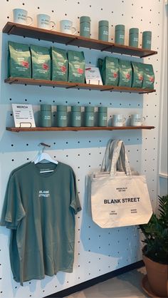 a store display with coffee cups and t - shirts hanging on the wall next to shelves