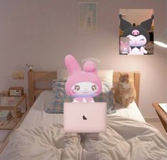 a cat sitting on top of a bed next to a pink bunny stuffed animal in front of a laptop computer