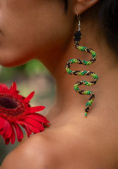 a close up of a person with a flower and earrings on their neck, next to a red flower