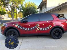 a red suv parked in front of a house with congratulations written on the side and gold stars