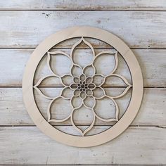 a circular metal wall decoration on a white wooden planks background, with an intricate flower design in the center