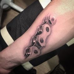 a close up of a person's arm with a tattoo on it that has chains