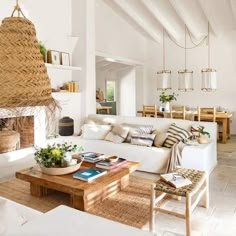 a living room filled with white furniture and lots of plants on top of the tables