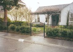 a house behind a fence with a for sale sign on the sidewalk