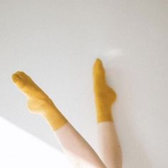 a woman's legs with yellow paint on them and her hand in the air