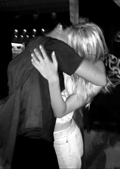 a man and woman embracing each other in front of a graffiti - covered wall at night