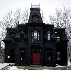 an old black house with red door and windows