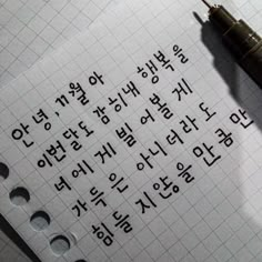 the writing is written in korean on a piece of paper with a pen next to it