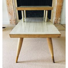 a small wooden table sitting in front of a fire place with no one on it