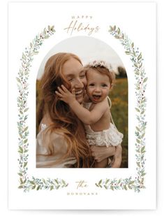 a woman holding a baby in her arms with the words happy holidays written on it