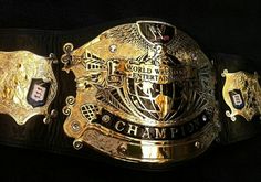 a gold belt with the words world wrestling championship written on it, and two black belts