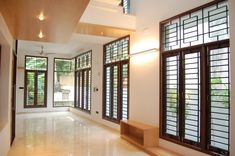 an empty room with large windows and wooden shutters on the walls, along with white tile flooring