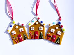 three decorated gingerbread houses hanging from red ribbon