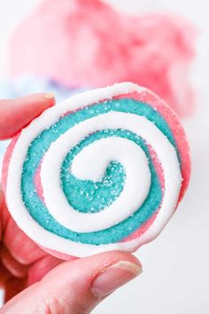 a hand holding a candy lollipop with blue and pink sprinkles