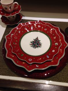 a red and white plate with a christmas tree on the center, surrounded by other plates