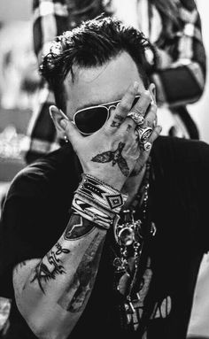 a man with tattoos and sunglasses covering his face