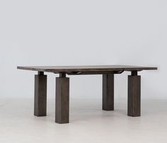 a large wooden table sitting on top of a white floor next to two black pillars