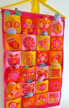 a pink and orange wall hanging with lots of different items on it's sides