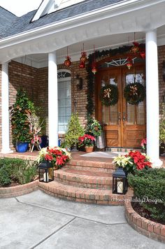 front porch decorated for the holidays with wreaths and poinsettias on the steps