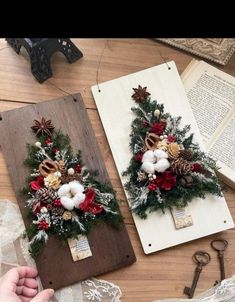 two christmas wreaths sitting on top of a wooden table next to scissors and other decorations