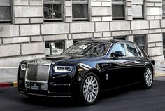 a black rolls royce parked in front of a building