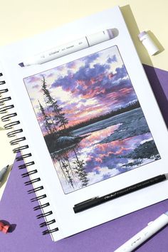 a notebook with some pastel crayons next to it on a purple surface