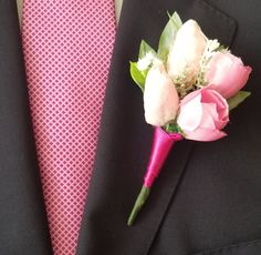 a pink boutonniere with white flowers on it and a red neck tie