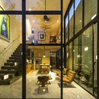 an open living room with stairs leading up to the top floor and glass doors on both sides