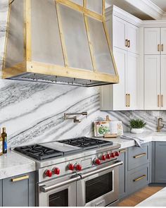 a kitchen with marble counter tops and stainless steel oven hood over the stove, surrounded by white cabinets