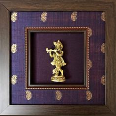 a gold statue in a wooden frame with purple wallpaper and pattern on the background