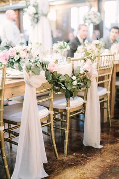 the table is set with white and pink flowers, greenery, and ribbons on it