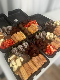 several trays filled with different types of desserts on top of a white table