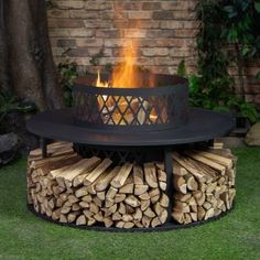 a fire pit sitting on top of a pile of wood next to a brick wall