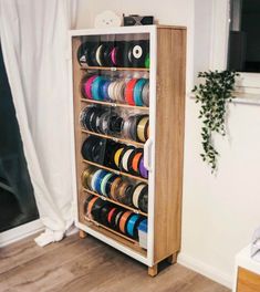 a wooden cabinet filled with lots of spools of thread