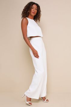 Sophisticated and flirty, the Lulus Timeless Disposition White Wide-Leg Two-Piece Jumpsuit will never go out of style! This impressive two-piece jumpsuit has a crepe woven fabrication that shapes a crop top with a crew neckline and a darted bodice with a top button closure and a keyhole-style cutout at the back. The matching pants have a high-waisted fit, darted details, and wide pant legs that fall to ankle-length hems. Pants have a hidden zipper/clasp at back. Fit: This garment fits true to si Chic Summer Wedding Sets, White Sleeveless Evening Sets, Elegant Fitted Two-piece Bottoms Set, Chic Two-piece Wide Leg Jumpsuits And Rompers, White Sleeveless Pantsuit For Night Out, Elegant Two-piece Summer Bottoms Set, Chic Two-piece Set, Elegant Summer Date Night Sets, Chic High Waist Two-piece Set