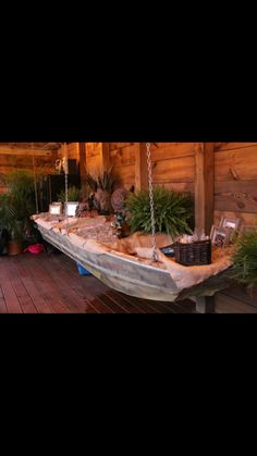 an old boat is sitting on the porch next to some potted plants and other things