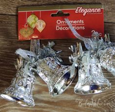 three silver bells are sitting next to each other on a wooden table with a red box