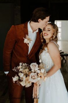 a bride and groom are posing for a photo in their wedding attire with flowers on the bouquet