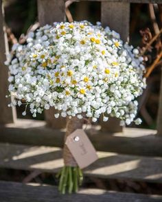 a bouquet of white and yellow flowers sitting on top of a wooden bench