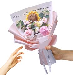 two hands are holding a bouquet of flowers