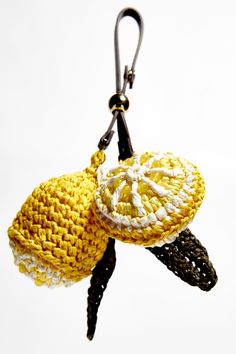 two crocheted objects hanging from a hook on a white background with black cord