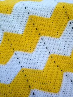 a yellow and white crocheted blanket with black dots on the edges is shown